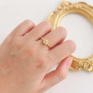 Bague de luxe en or avec cristal jaune carré et anneau tressé sur une main