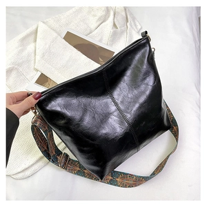 Detail of black faux leather tote featuring a vibrant ethnic print wide shoulder strap