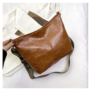 Brown vintage faux leather tote bag with retro wide shoulder strap on white fabric