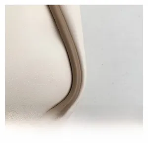 Macro shot of cream faux leather bucket bag detailing with brown contrast piping edge