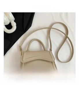 Detail view of beige trapezoid handbag with wavy textured flap and gold metal hardware