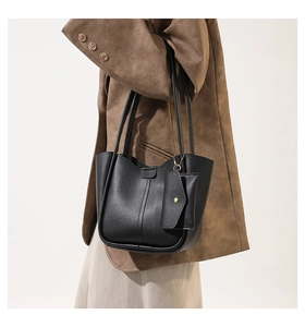 Detail view of black leather bucket bag with decorative stitching and matching coin pouch