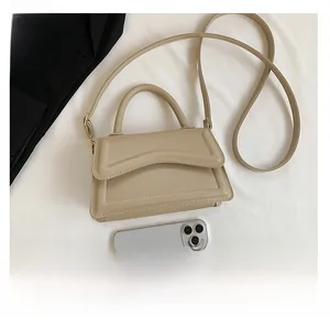 Beige rectangular crossbody bag with wave flap shown next to a phone for size reference