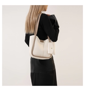 Detail of minimalist cream leather tote bag featuring khaki contrast trim and mini pouch