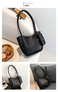 Close-up of minimalist black bucket bag with matching mini pouch and cross-stitch detail
