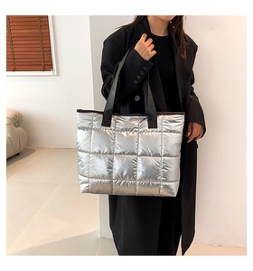 Detail of silver metallic quilted tote bag with square pattern and black straps