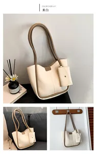 Detail view of creamy white tote bag set with brown trim on sofa and wall hook display