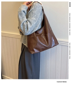 Close-up of a large brown leather tote bag showing textured stitching and shoulder strap