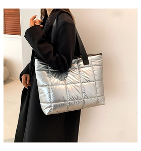 Detail view of silver quilted tote bag with metallic finish and black woven strap