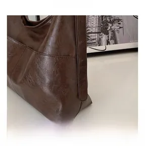 Detail of dark brown leather tote bag with adjustable shoulder strap and visible stitching