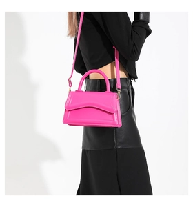 Side view of model wearing a glossy rose pink crossbody bag with wavy flap design