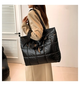 Detail view of large black quilted puffer tote bag shown on model for size and fit