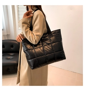 Side view of model wearing a black quilted puffer tote bag with spacious interior