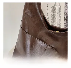 Detail view of brown leather tote showing fine stitching and gold magnetic closure buckle