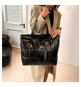 Detail of black quilted puffer tote bag showing padded texture and dual shoulder straps
