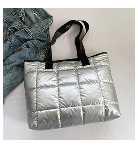 Detail of silver quilted tote bag with metallic finish and black nylon webbing straps