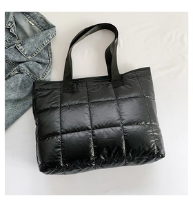 Detailed close-up of black quilted puffer tote bag with durable nylon woven straps
