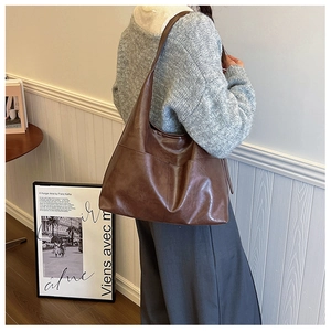 Deep brown matte leather tote bag with structural stitching details shown on model