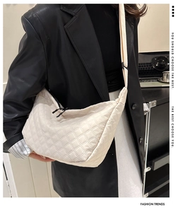 Detail of beige quilted nylon crossbody bag featuring dual zippers and adjustable wide strap