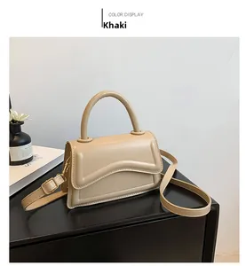 Detailed view of khaki crossbody bag with curved flap design and adjustable shoulder strap