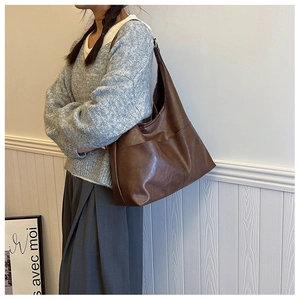 Detailed view of deep brown vintage faux leather tote bag worn by a model in a minimal setting