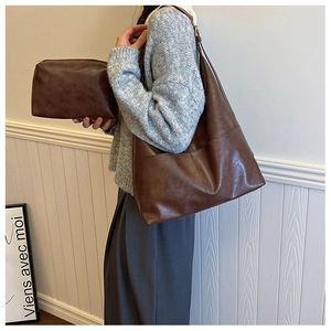 Close-up of vintage brown leather hobo bag and matching pouch worn by model