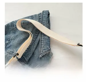 Detail of blue denim and white quilted fabric with canvas strap on a shoulder bag