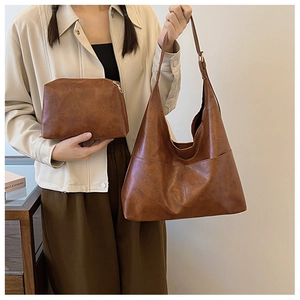Detail of dark caramel retro leather hobo bag and matching pouch on a model's shoulder