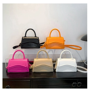 Collection of minimalist square handbags in five colors displayed on acrylic stands