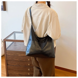 Detail shot of a black leather tote bag showing smooth texture and large capacity design