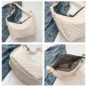 Detail view of cream quilted shoulder bag with interior space and adjustable strap