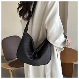 Detail of black quilted nylon crossbody bag with dual zippers and adjustable shoulder strap