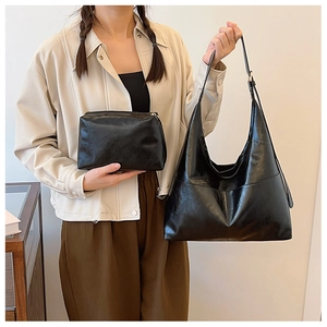 Detail of minimalist black leather tote and matching small pouch held by a model