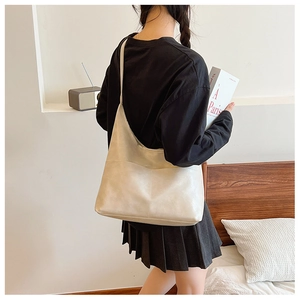Minimalist beige PU leather tote bag with a front pocket shown on a model's shoulder