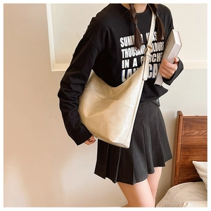 Detail view of the cream-colored hobo tote bag with adjustable strap and side pocket
