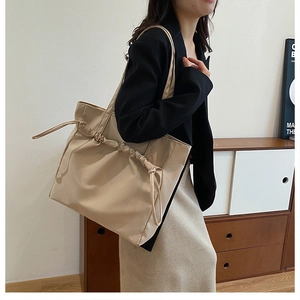 Détails des plis à cordon et de la bandoulière fine sur un grand sac cabas beige