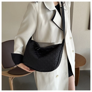 On-body shot of a large black quilted nylon hobo bag with a wide fabric shoulder strap