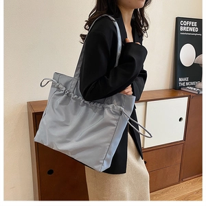 Sac fourre-tout bleu tricoté avec cordon de serrage montré en porté épaule décontracté