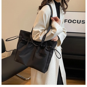 Détail d'un grand sac fourre-tout noir plissé en tissu tricoté avec cordon de serrage