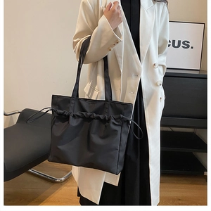 Détail du sac cabas noir avec cordon de serrage montrant la texture plissée en nylon
