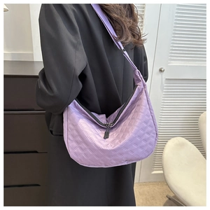 Detailed back view of a purple quilted nylon dumpling bag with adjustable strap on model