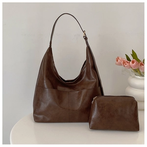 Detail of dark brown tote bag with vintage wax texture and matching small zipper pouch