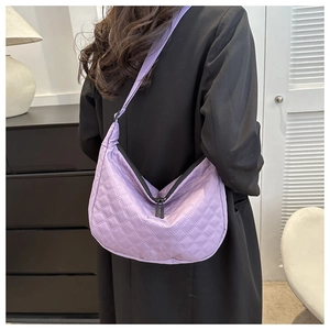 Detail of purple quilted hobo bag featuring diamond pattern and wide shoulder strap