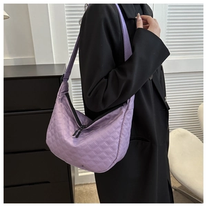 Close-up of purple quilted nylon crossbody bag with diamond stitching and wide strap