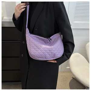 Detailed view of purple quilted nylon crossbody bag with adjustable strap worn by a model