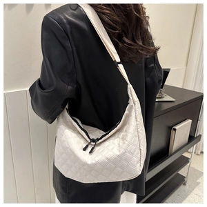 Detail view of cream quilted hobo bag with nylon texture and black zipper hardware