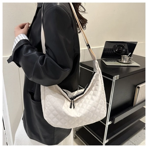 White quilted nylon hobo bag with black double zippers and wide strap worn by a model