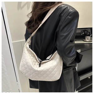 Detailed view of white quilted nylon crossbody bag with black zipper and wide shoulder strap