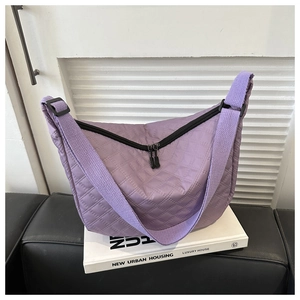 Detail shot of purple quilted nylon crescent bag with textured diamond stitching and black zippers