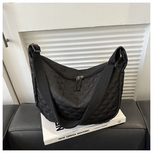 Detail of black quilted nylon crescent bag with wide strap and double zippers